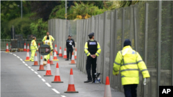 Oficerët e policisë bëjnë roje pranë gardhit që qarkon Kështjellën Tregenna, Cornwall, Angli (9 qershor 2021)