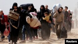 People walk with their belongings as they flee the rebel-held town of Hammouriyeh, eastern Ghouta, Syria, March 15, 2018.