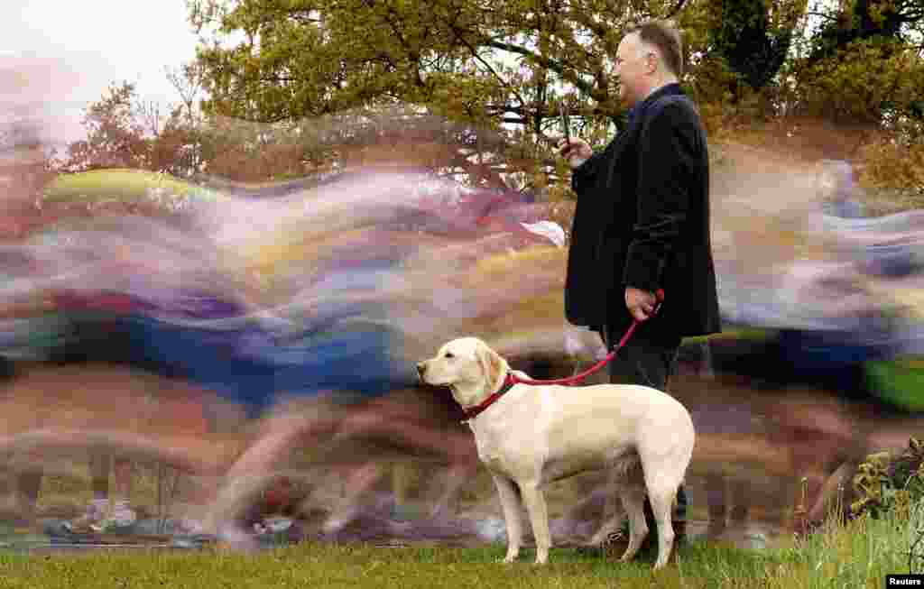 A man with a dog watches runners the start of the London Marathon in Blackheath, England.