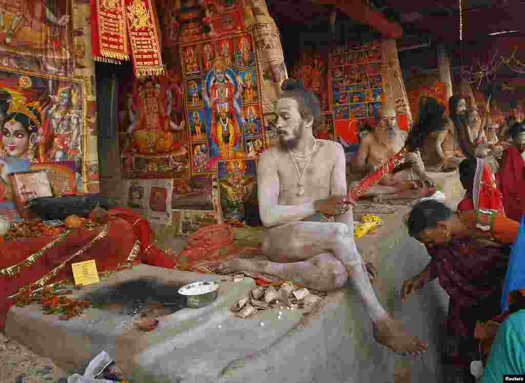 Seorang perempuan Hindu meminta berkah dari Naga Sadhu, atau orang suci agama Hindu dalam upacara keagamaan di Pulau Sagar, selatan kota Kolkata, India.