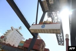 FILE - Shipping containers are offloaded from a cargo ship at Port Everglades, June 24, 2016, in Fort Lauderdale, Fla.