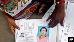 Relatives of Kasthuri Munirathinam display a photo of her and copies of her employment documents, in Chennai, India, Oct. 24, 2015.