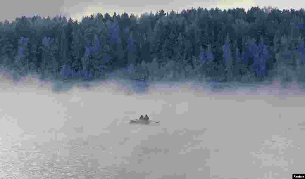 Two men row a boat through a frosty fog along the Yenisei River in the Taiga district outside the Siberian city of Krasnoyarsk, Russia.