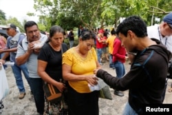 Relatives of victims of the eruption of the Fuego volcano receive food from volunteers outside the morgue in Escuintla, Guatemala, June 7, 2018.