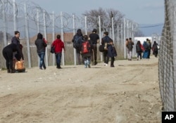 FILE - Migrants walk to registration and transit camp after entering Macedonia from Greece near the southern Macedonian town of Gevgelija, Saturday, March 5, 2016.