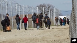 FILE - Migrants walk to registration and transit camp after entering Macedonia from Greece near the southern Macedonian town of Gevgelija, Saturday, March 5, 2016.