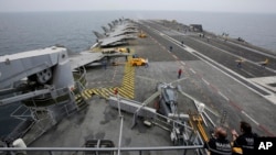 FILE - French sailors work on the flight deck of the French Navy aircraft carrier Charles de Gaulle in the Persian Gulf, March 17, 2015. 