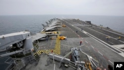 FILE - French sailors work on the flight deck of the French Navy aircraft carrier Charles de Gaulle in the Persian Gulf, March 17, 2015. 