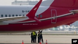 Ground crew members chat near a Boeing 737 MAX 8 plane operated by Shanghai Airlines parked on tarmac at Hongqiao airport in Shanghai, China, March 12, 2019. 