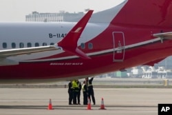 Ground crew chat near a Boeing 737 MAX 8 plane operated by Shanghai Airlines parked on tarmac at Hongqiao airport in Shanghai, China, March 12, 2019.