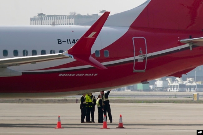 Ground crew chat near a Boeing 737 MAX 8 plane operated by Shanghai Airlines parked on tarmac at Hongqiao airport in Shanghai, China, March 12, 2019.
