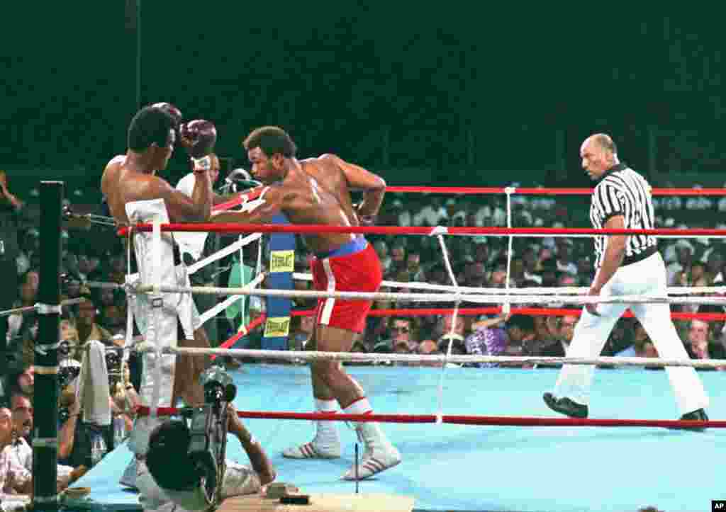 George Foreman, centre, décroche un coup de poing sur Muhammad Ali au cours du combat de championnat WBA, à Kinshasa, Zaïre, le 30 octobre 1974. L&rsquo;arbitre Zack Clayton est à droite. Ali a remporté par K.O au cours du huitième round. (AP Photo) 