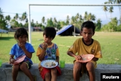 Anak-anak makan di luar tenda mereka untuk alasan keamanan, setelah gempa bumi di desa Biromaru di Sigi, Sulawesi, Indonesia, 3 Oktober 2018.