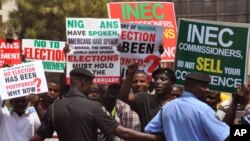 Police provide security as people demonstrate in Abuja, Nigeria, against the postponement of Nigerian elections, Feb. 7, 2015.