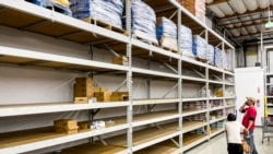 FILE - A man browses largely empty shelves for cat food at Pet Club on Nov. 18, 2021, in Emeryville, California. According to store employees, supply chain issues are preventing the store from keeping products stocked.