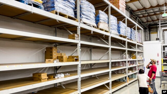 A man browses largely empty shelves for cat food at Pet Club on Nov. 18, 2021, in Emeryville, California. According to store employees, supply chain issues are preventing the store from keeping products stocked.