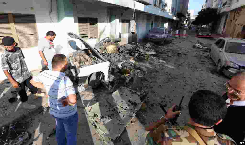 Libyan security forces inspect the remains of a vehicle near the Ministry of Interior in Tripoli after twin blasts hit the Libyan capital, August 19, 2012.