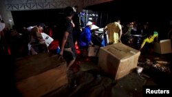 People carry looted goods as they walk through a flooded street in Acapulco, Sept. 18, 2013. 