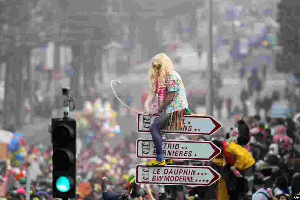 A participant sits on a sign as people dance in the street as they take part in the student carnival in Caen, northwestern France. 