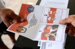 Seorang petugas TPS memberikan surat suara di TPS di Kuta, Bali, saat pelaksanaan pilkada, 9 Desember 2015. (Foto: AFP)