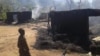 Two children walk by still smoldering houses in the village of Chukudum, where South Sudanese soldiers went on a deadly rampage on Tuesday, Oct. 7, 2014.