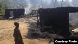 Two children walk by still smoldering houses in the village of Chukudum, where South Sudanese soldiers went on a deadly rampage on Tuesday, Oct. 7, 2014.