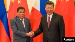 FILE - Chinese President Xi Jinping, right, shakes hands with Philippines President Rodrigo Duterte before their bilateral meeting during the Belt and Road Forum, Beijing, May 15, 2017.