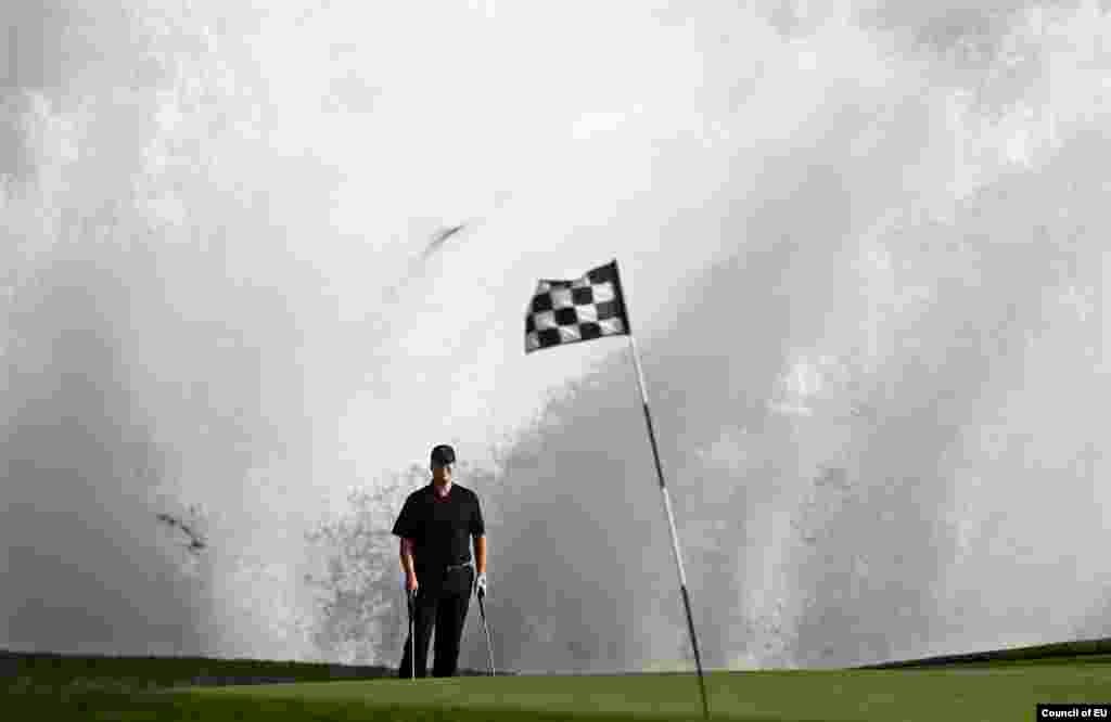 A wave crashes behind Todd Linehan on the 18th green at Pebble Beach Golf Links in Pebble Beach, California.