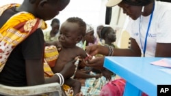 FILE - In this photo of Friday, July 25, 2014, a child with suspected malnutrition is examined at IMC nutrition program clinic in Malakal, South Sudan. 
