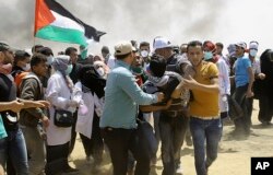 Palestinian protesters evacuate a wounded youth near the Israeli border fence, east of Khan Younis, in the Gaza Strip, May 14, 2018.