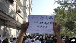 People protest against Syria's President Bashar al-Assad on the first day of Eid Al-Fitr in the city of Suqba August 30, 2011. The banner reads: "Need international intervention to protect us from Bashar's gangs", August 30, 2011.