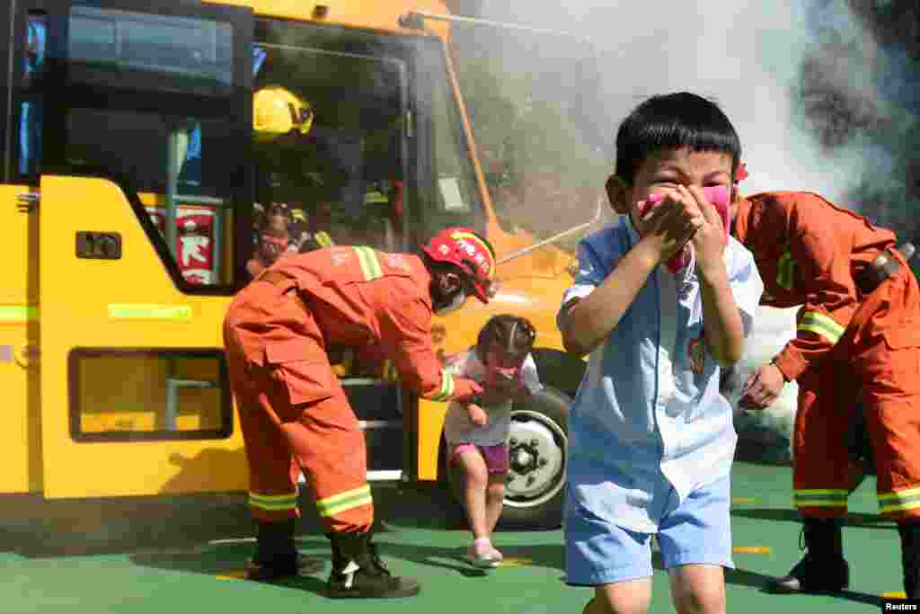 Firefighters instruct children evacuating a school bus during a fire drill at a kindergarten in Cangzhou, Hebei province, China, Aug. 27, 2018.