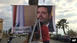 Workers hang a poster of outgoing Prime Minister Saad Hariri with Arabic words that read "We are all Saad," on a seaside street in Beirut, Lebanon, Nov. 9, 2017.