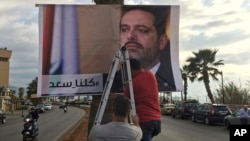 Workers hang a poster of outgoing Prime Minister Saad al-Hariri with Arabic words that read "We are all Saad," on a seaside street in Beirut, Lebanon, Nov. 9, 2017. Hezbollah has called on Saudi Arabia to stay out of Lebanese affairs, saying the resignation of Hariri "has raised many questions."