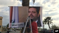 Pekerja memasang poster Perdana Menteri Saad al-Hariri yang mengundurkan diri di sebuah jalan di pinggir pantai Beirut, Lebanon, 9 November 2017. Pada poster itu tertulis kata-kata Arab yang berbunyi "Kami semua adalah Saad."