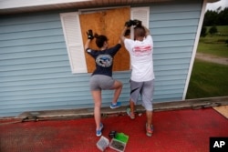 Haley Sensebe, left, and Bernard Oser board up their home in Violet, La., in preparation for Hurricane Nate, expected to make landfall on the Gulf Coast, Oct. 7, 2017.