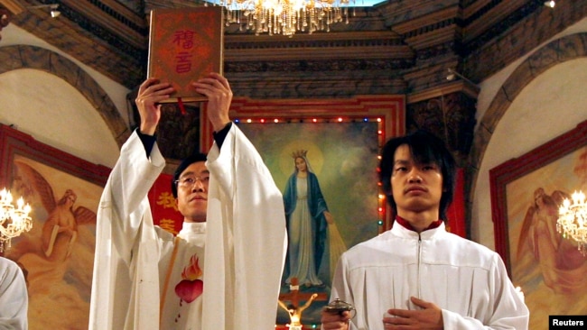 资料照： 北京天主教堂里的一名神职人员在做圣诞弥撒时高举中文版的圣经。（2007年12月24日）