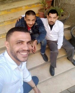 This photo taken in March 2020 provided by Egyptian coffee shop worker Hany Hassan, shows the father of four Hany Hassan, at right, and his friends taking a 'selfie' outside the coffee shop where he works, in Cairo, Egypt. (Courtesy of Hany Hassan via AP)