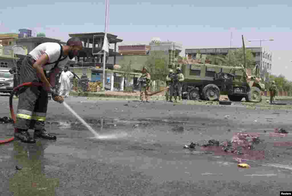 A fireman clears blood and debris as NATO soldiers stand at the site of an attack in Helmand province, Afghanistan, August 28, 2013.