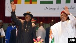 Nigeria's President Goodluck Jonathan (L) and Niger's President Mahamadou Issoufou wave while taking part in a regional summit focused on the fight against Nigerian Islamist extremist group Boko Haram, Oct. 7, 2014 in Niamey.