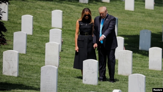 El presidente de los Estados Unidos, Donald Trump, y la primera dama, Melania Trump, se agarran de las manos entre las lápidas mientras participan en el evento anual "Flags-In" en el Cementerio Nacional de Arlington. Photo: Reuters.