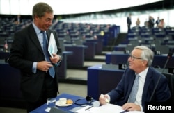 European Commission President Jean-Claude Juncker, right, talks with Nigel Farage, United Kingdom Independence Party member and member of the European Parliament, ahead of debate at the parliament in Strasbourg, France, Sept. 13, 2017.