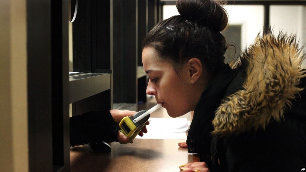 In this September 21, 2015, file photo, Autumn Regimbal blows into a Breathalyzer in the wing of the county jail dedicated to the state's 24/7 Sobriety Program in Sioux Falls, S.D. (AP Photo/Jay Pickthorn, File)