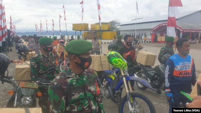 Personel TNI-POLRI menggunakan sepeda motor mendistribusikan bingkisan bantuan sosial untuk masyarakat Poso Pesisir, Kabupaten Poso, Sulawesi Tengah. Rabu (23/12/2020). (Foto: VOA/Yoanes Litha)