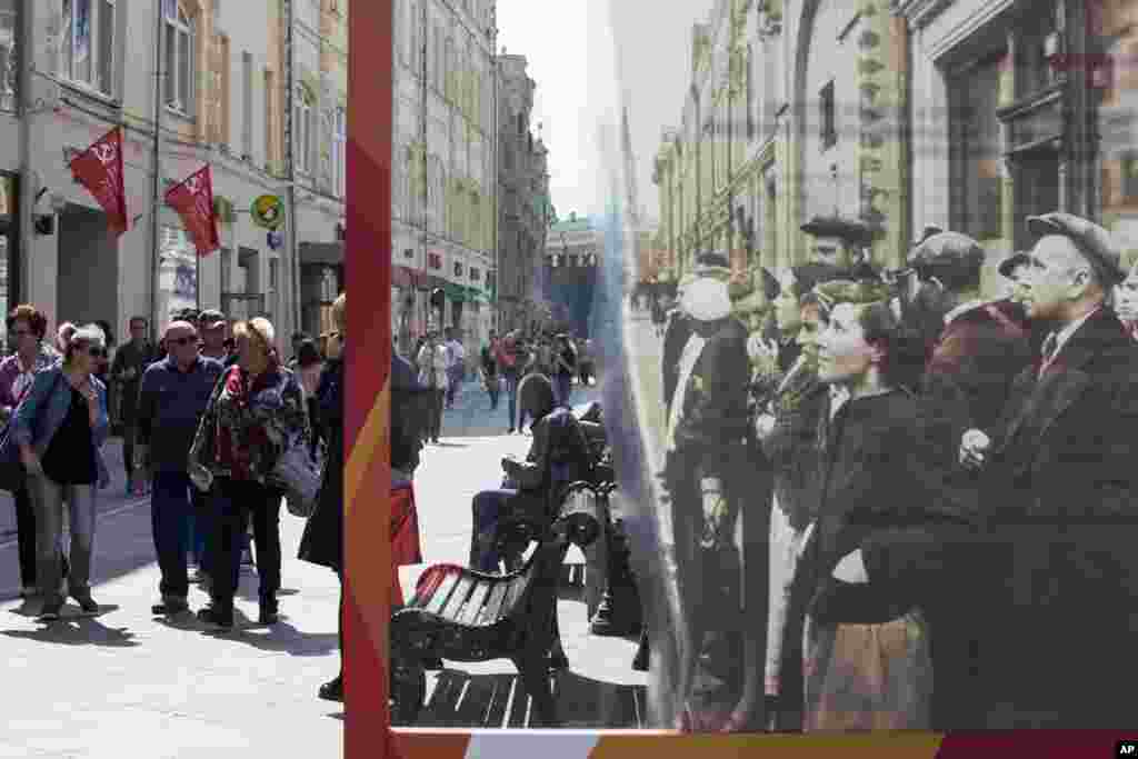 People walk by a poster showing a World War II-era photo of people listening to news, and installed in preparation for Victory Day celebration just off Red Square in Moscow. Victory Day commemorates the 1945 defeat of Nazi Germany in World War II.