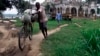 A bicyclist carries a bag of rice to market on the banks of the Congo river in Kisangani in rebel-held Congo, Thursday, Aug. 1, 2002.