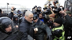 Police officers detain opposition activist Sergei Udaltsov outside the NTV television station in Moscow, Sunday, March, 18, 2012.