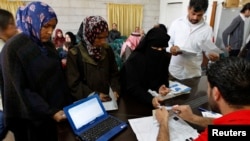 Syrian refugees receive humanitarian aid shopping vouchers at a distribution center of the World Food Program (WFP) organization in Amman April 11, 2013. The U.N. refugee agency and the WFP are distributing shopping vouchers to 170,000 Syrian refugees. 