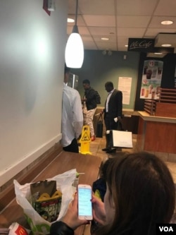 Chatunga Mugabe with a security aide at a McDonald's outlet in New York, USA, carrying Gucci products.