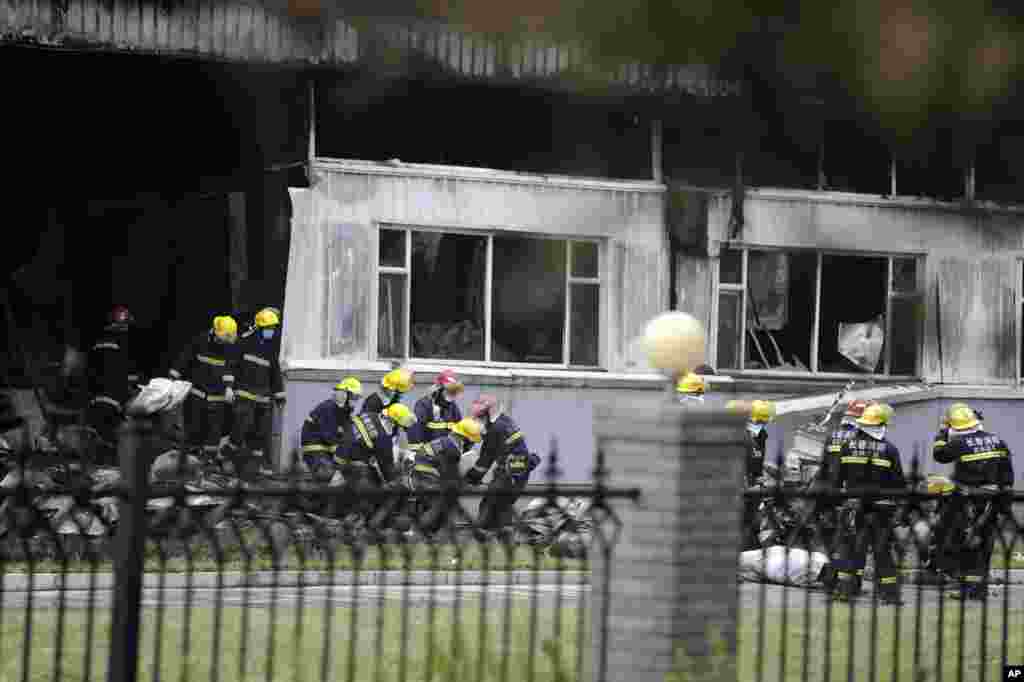 Firemen carry out bags containing bodies of those killed at a poultry processing plant that was engulfed by a fire in northeast China's Jilin province's Mishazi township, June 3, 2013.